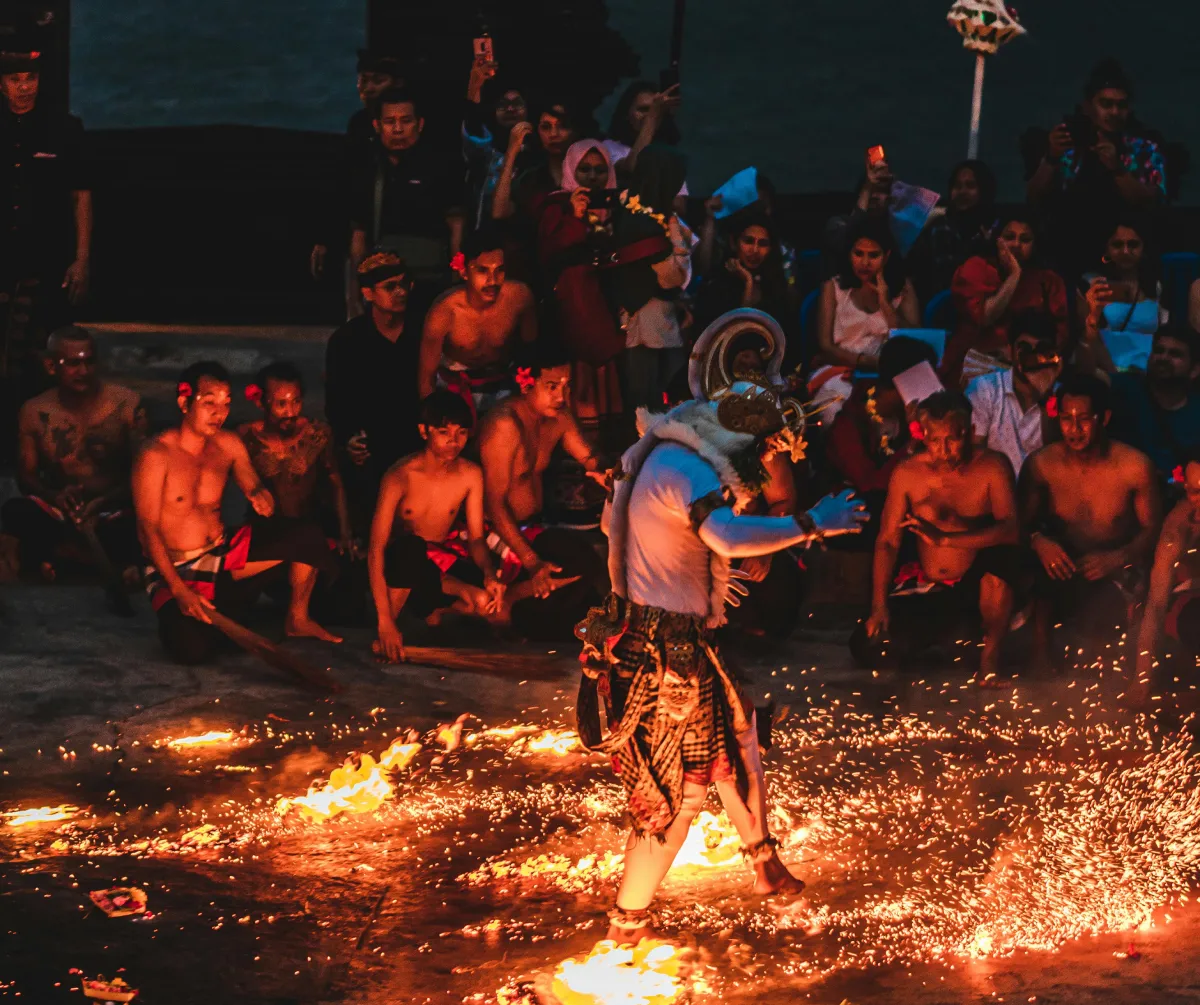 Group of adults performing traditional dance at a music festival amidst flames, symbolising cultural celebration