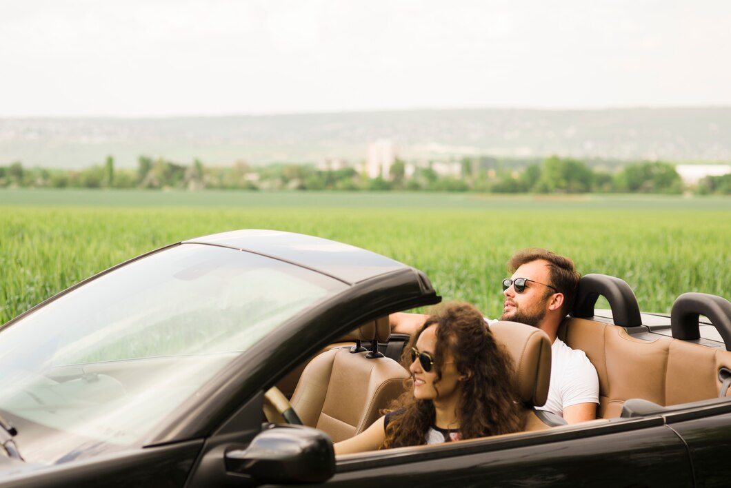 Happy woman enjoying summer travel in a convertible car in a beautiful outdoor landscape.