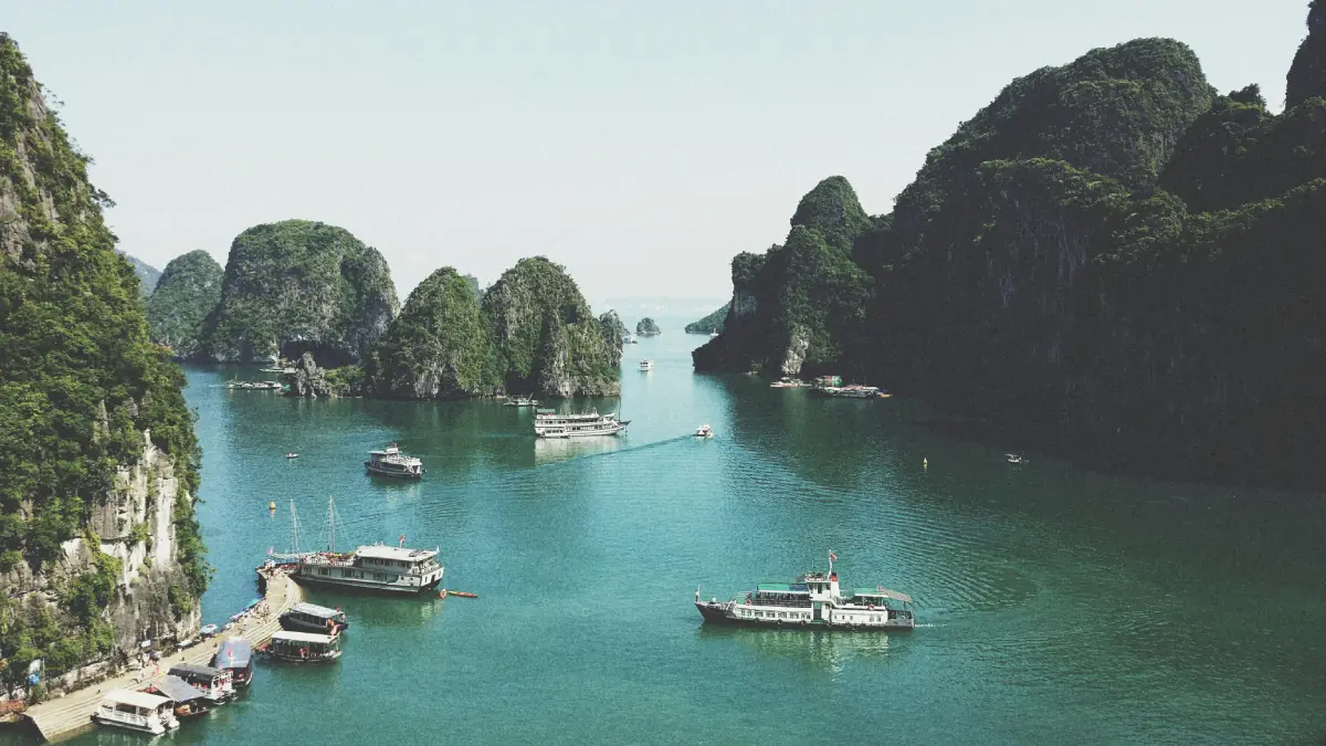 Boat anchored in a bay near a lush island during a sunny summer day
