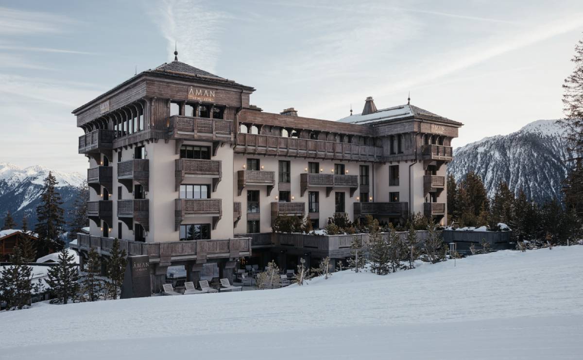 Winter resort chalet covered in snow surrounded by icy trees, on a clear daylight, no person visible.