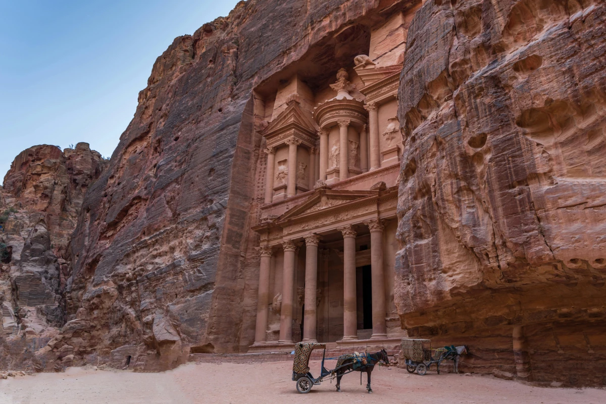Scenic view of ancient sandstone architecture in a narrow desert canyon under a clear sky