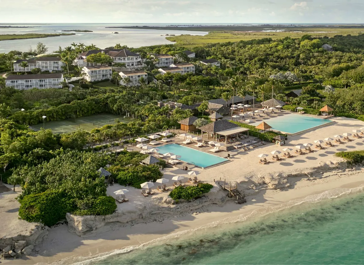 Idyllic island scenery with tranquil sea, sandy beach, tropical trees and architectural beauty in daylight.