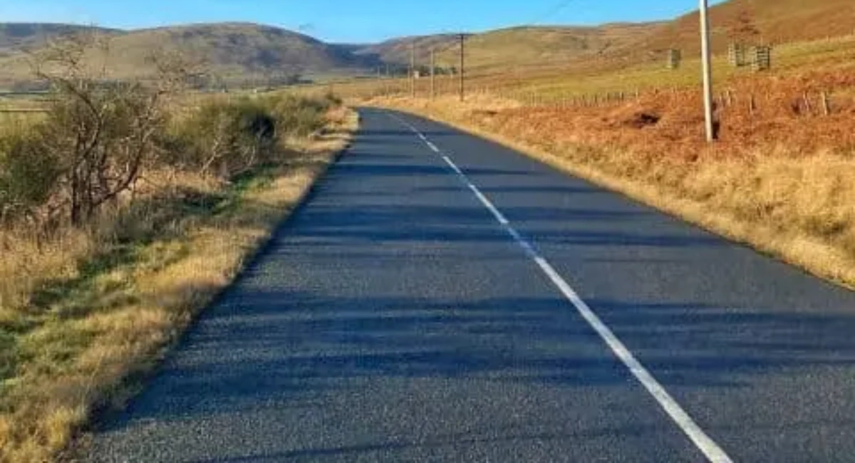 Empty asphalt road curving through panoramic desert landscape under a clear sky during a trip