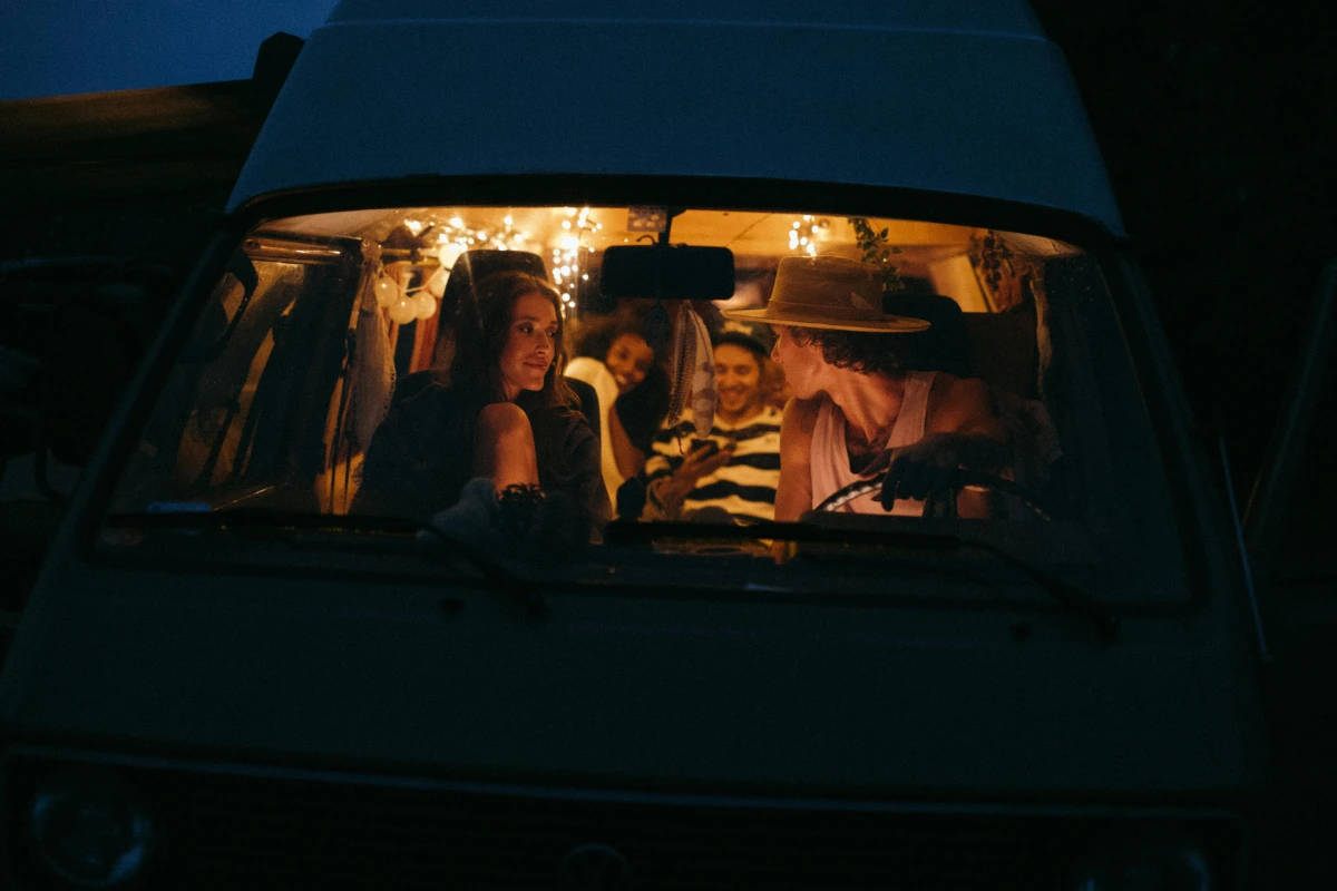 Man and woman smiling in a car during a road trip, seen through vehicle window