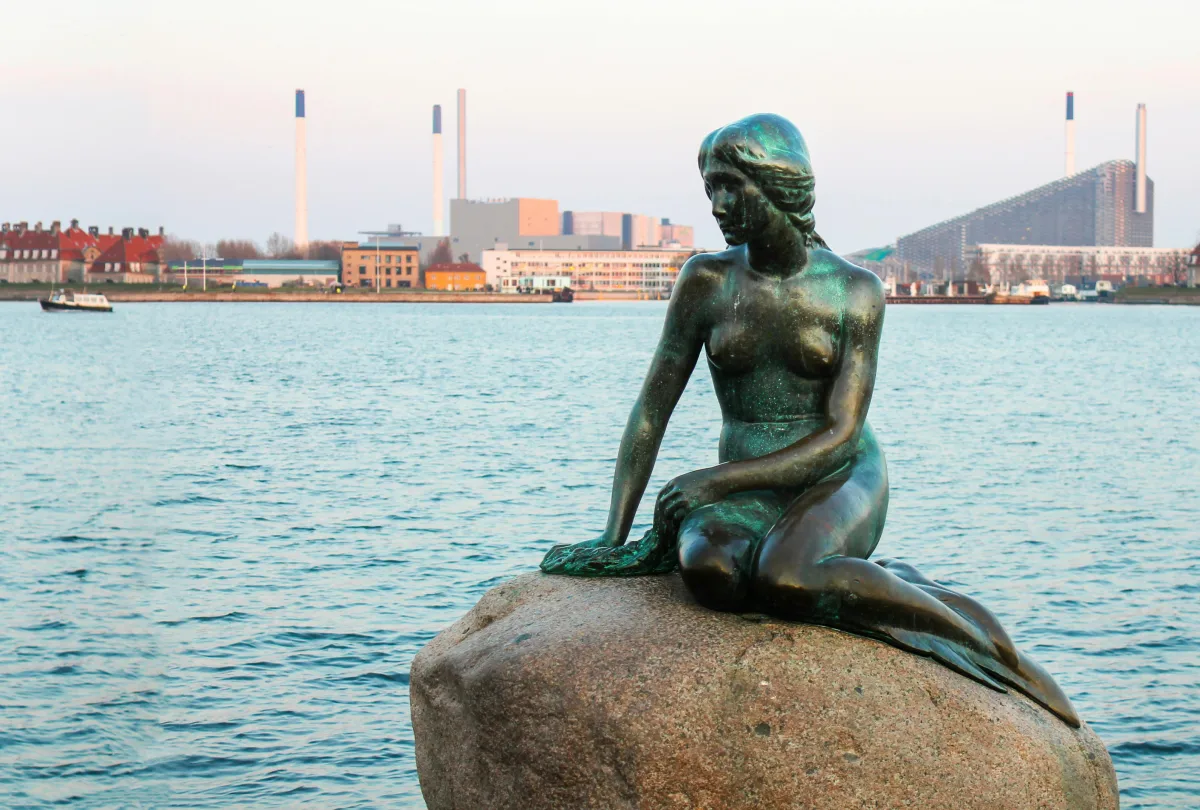 Bronze sculpture on a city bridge overlooking a river with boats and urban skyline