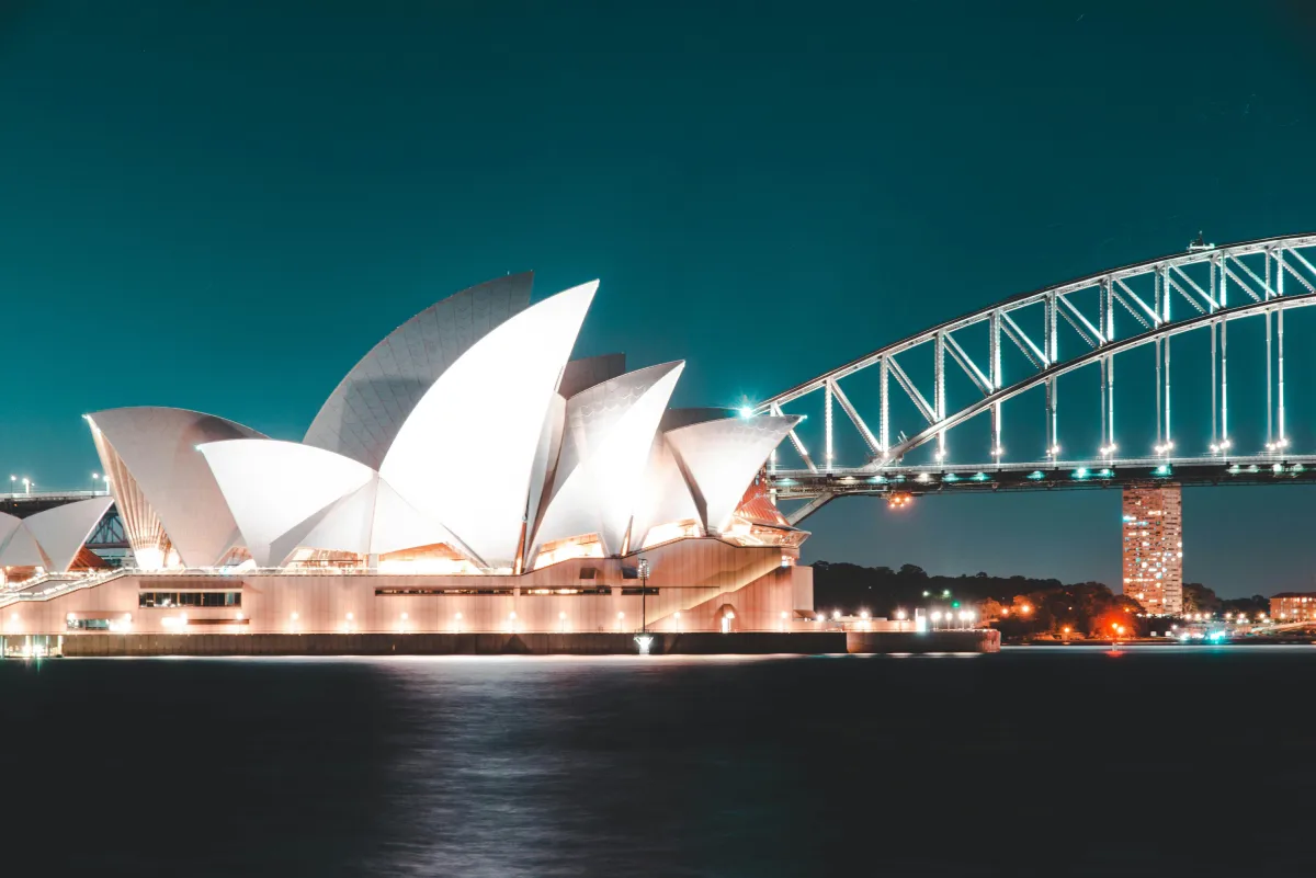 Architectural silhouette of a cityscape with bridge and opera at dusk over the tranquil bay