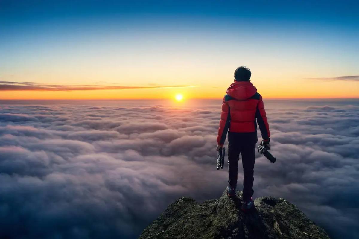 a man is standing on a peak and viewing sunset