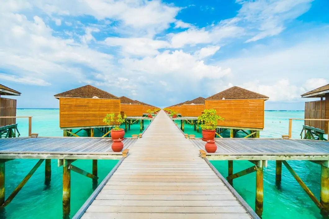 Tropical luxury resort on sandy beach with clear ocean under fair weather sky