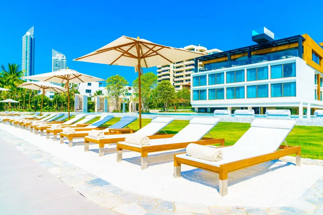 Luxury resort patio with a sofa chair by the dug-out swimming pool under a beach umbrella.