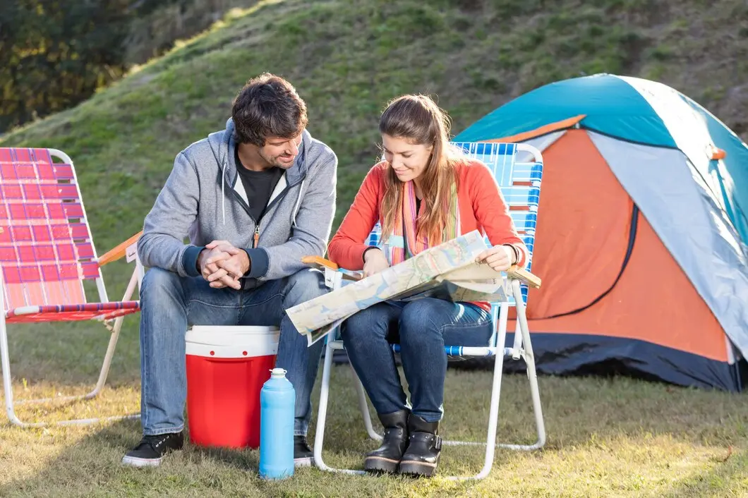 Happy family camping in summer at park, with couple, child and camper set up in leisurely outdoors