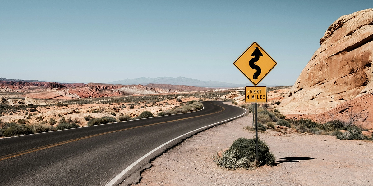Empty desert highway stretching towards distant mountains under a clear sky, perfect for outdoor travel.
