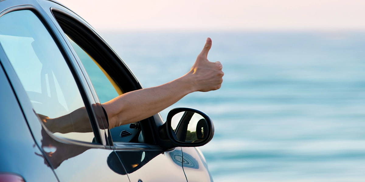 A hand giving a thumbs up from a car window.