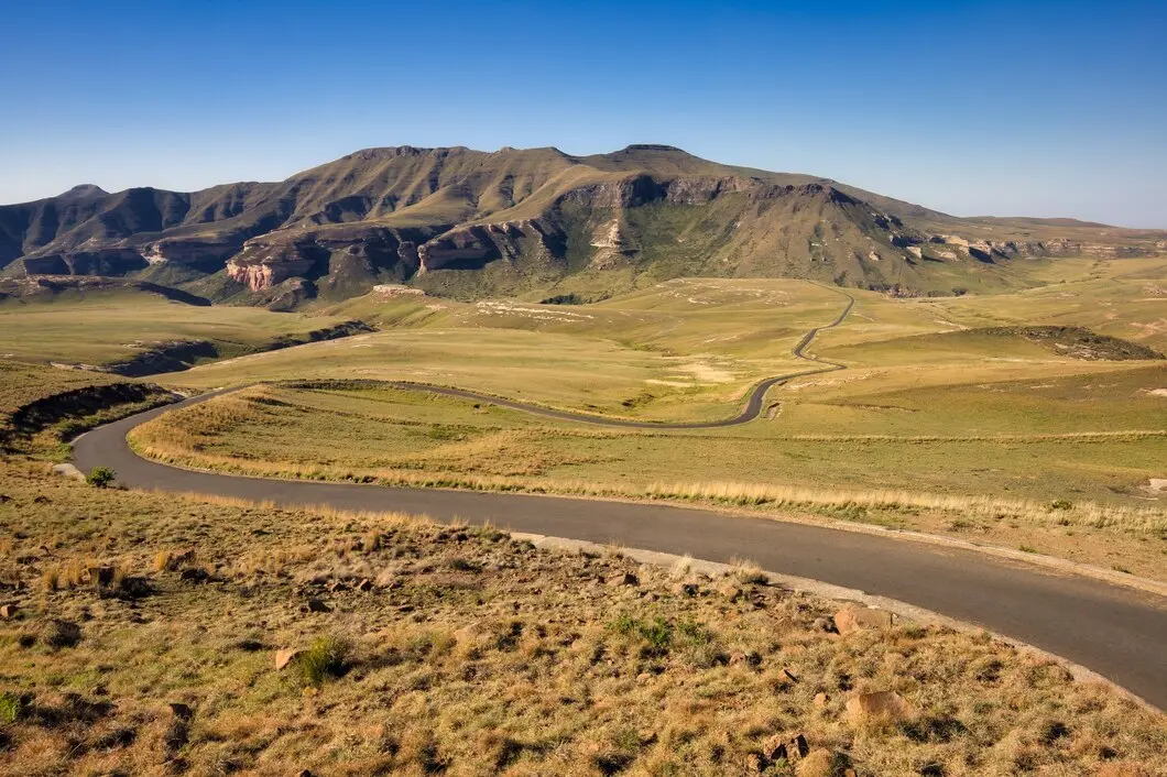 Scenic view of a deserted valley with cropland, blue sky, grassland and distant mountains