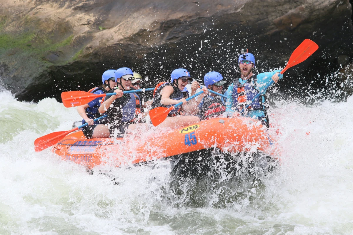 Sportsmen in a kayak competition racing through river rapids, stirring up water splashes